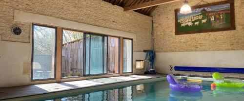a swimming pool with inflatable chairs in a room at La Fresnée chambres d'hôtes in Mosles
