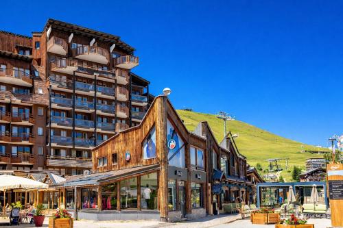 a building in front of a building with a hill in the background at Résidence Pierre & Vacances L'Ours Blanc in L'Alpe-d'Huez