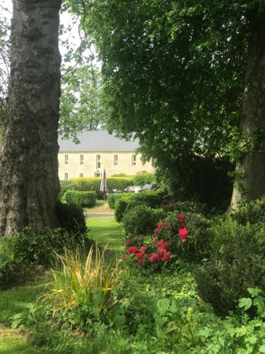 a garden with flowers and trees and a building at La Fresnée chambres d'hôtes in Mosles
