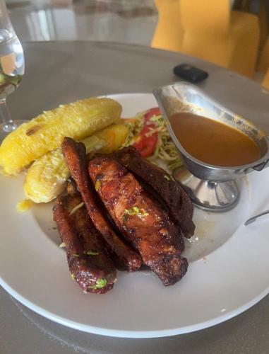 a plate of food with meat and sausage and a drink at BUDDIEZ hotel limited in Kampala