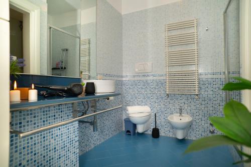 a blue tiled bathroom with a toilet and a sink at Corte Cavour Duplex Gallarate centro, Wifi e Garage in Gallarate