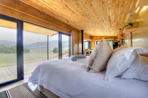 a bedroom with a large bed with a large window at Giantscup Wilderness Reserve in Underberg