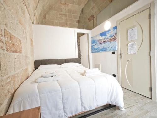 a white bed in a room with a brick wall at Azzurro A Mare in Polignano a Mare
