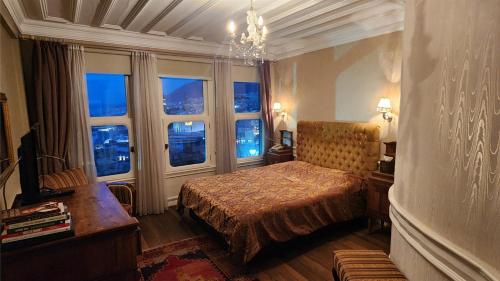 ein Schlafzimmer mit Bett, Fenstern und Kronleuchter in der Unterkunft Kitapevi Hotel in Bursa