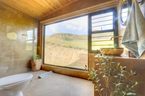 a bathroom with a toilet and a large window at Giantscup Wilderness Reserve in Underberg