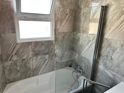 a bathroom with a shower and a tub and a window at Capelas Pdl Apartment in Ponta Delgada