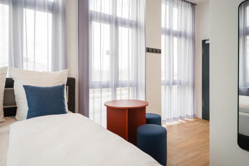 a bedroom with a bed and a table and windows at Homaris Rummelsburg Studios in Berlin