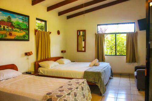 a hotel room with two beds and a window at Hotel Colinas del Sol in Atenas