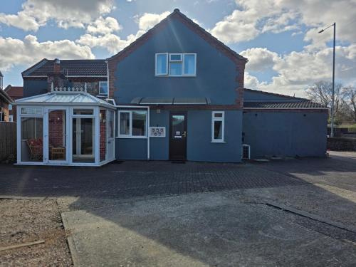a blue house with a garage in a parking lot at Mount Lavinia in Sheringham