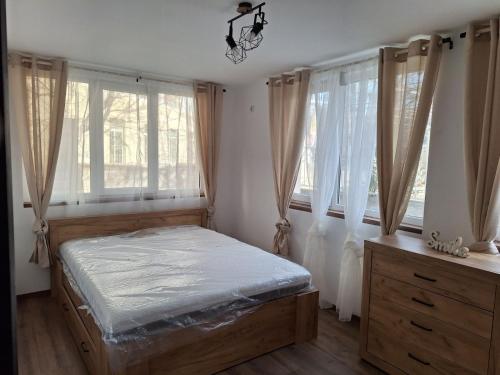 a bedroom with a bed and two windows at Апартамент Бохо 2 in Primorsko