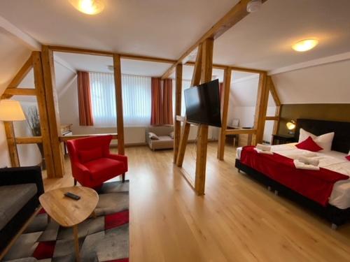 a room with a bed and a couch and a television at "Landidyll"Hotel Rathaus in Wildemann