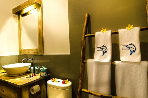 a bathroom with a sink and a toilet and towels at Blue Marlin Dive Resort Trawangan in Gili Trawangan