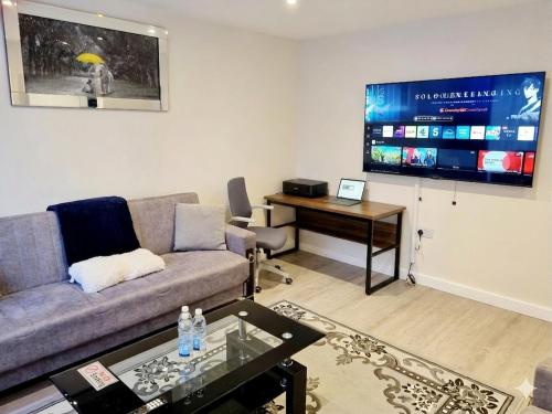 a living room with a couch and a large screen at 3bed 2bath House-Free Parking-Fast WiFi-Garden-Entire Home-2mins from Train Station-Sleeps 6 in London