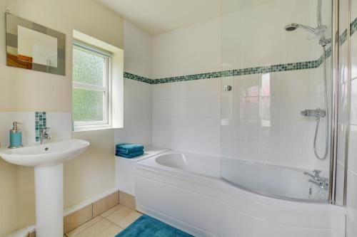 a white bathroom with a tub and a sink at 1 Bed in Bergh Apton oc-1387 in Thurton