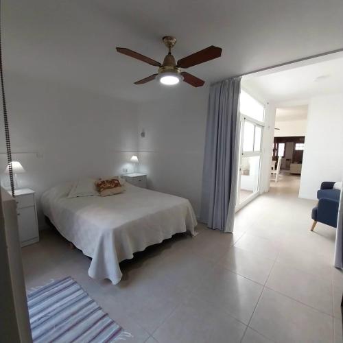 a white bedroom with a bed and a ceiling fan at La Ñata Apart in Junín