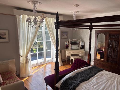a bedroom with a canopy bed and a large window at Plas Dolguog in Machynlleth