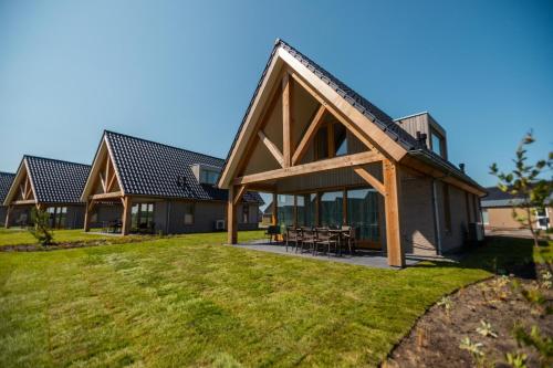 a large house with a gambrel roof with a patio at EuroParcs Cadzand-Bad in Cadzand