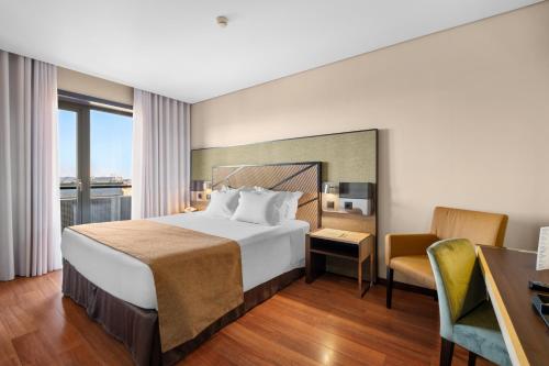 a hotel room with a bed and a desk and chair at Axis Porto Business & Spa Hotel in Porto
