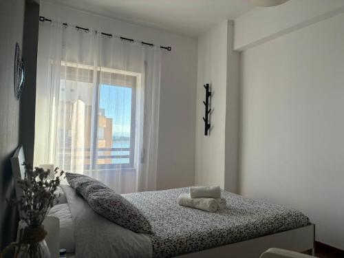 a white bedroom with a bed with a window at Vieira's House in Barreiro