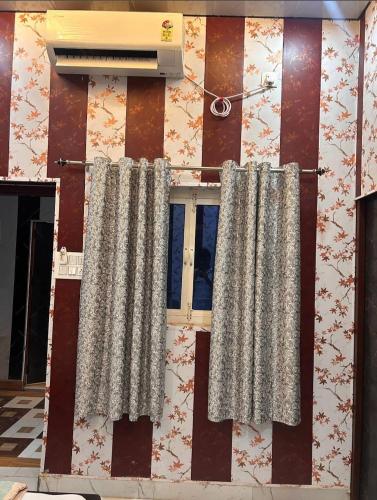 a wall with two curtains and a window at anandam stay in Vrindāvan