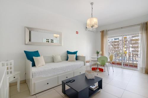 a white room with a bed and a table at Casa De Pardal in Quarteira
