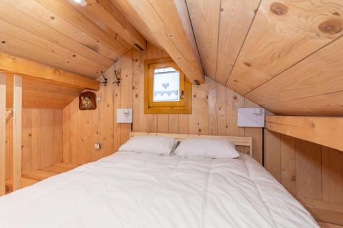 a bed in a wooden cabin with a window at The Little Cottage in Alleghe