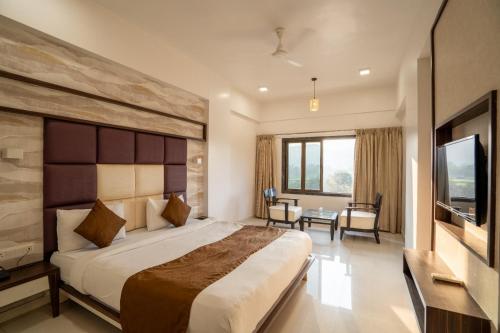 a hotel room with a bed and a television at Krushnai Resort in Kharakvasla
