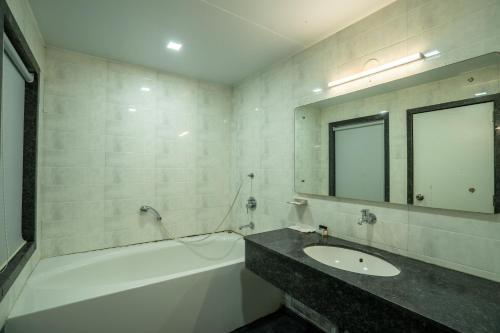 a bathroom with a sink and a tub and a mirror at Krushnai Resort in Kharakvasla