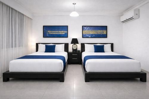 a bedroom with two beds with blue and white sheets at Hotel Galerias HN in San Pedro Sula
