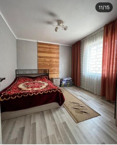 a bedroom with a bed with a red blanket at Коттедж in Cholpon-Ata