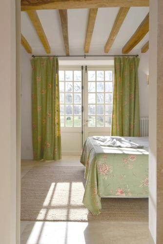 a bedroom with a bed with green curtains and a window at La Roseraie in Barjouville