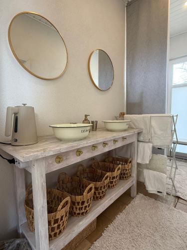 a bathroom with two sinks and baskets and mirrors at Ferienhaus an der Allee in Kalkar
