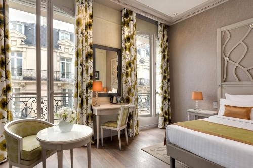 a bedroom with a bed and a desk and a window at Hôtel Château Frontenac in Paris