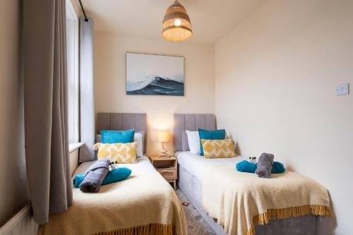 two beds in a room with blue and yellow at Central Apartment- Stunning Sea Views- 100m to Beach- Sleeps 6 in Newquay