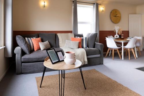 a living room with a couch and a table with a laptop at Central Apartment- Stunning Sea Views- 100m to Beach- Sleeps 6 in Newquay