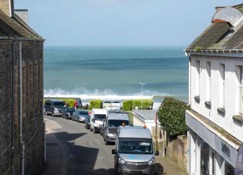 a line of cars parked on a street near the beach at Central Apartment- Stunning Sea Views- 100m to Beach- Sleeps 6 in Newquay