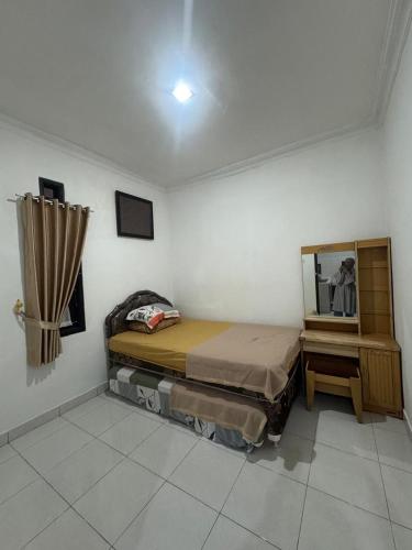 a small bedroom with a bed and a mirror at laksana homestay in Cireungit