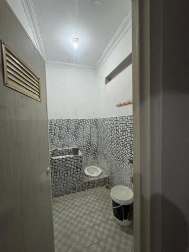 a bathroom with a toilet and a tiled floor at laksana homestay in Cireungit