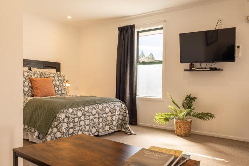 a bedroom with a bed and a tv on a wall at The Dales in Twizel