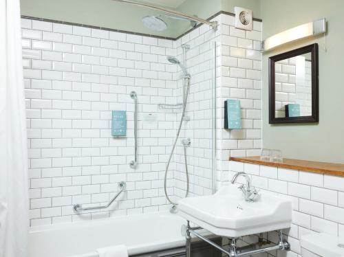 a white bathroom with a sink and a shower at St Leonards Hotel by Greene King Inns in Saint Leonards