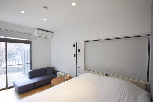 a bedroom with a bed and a couch and a window at リノベーションされた一軒家で富士山と自然 BBQを満喫 villa voyage in Azagawa