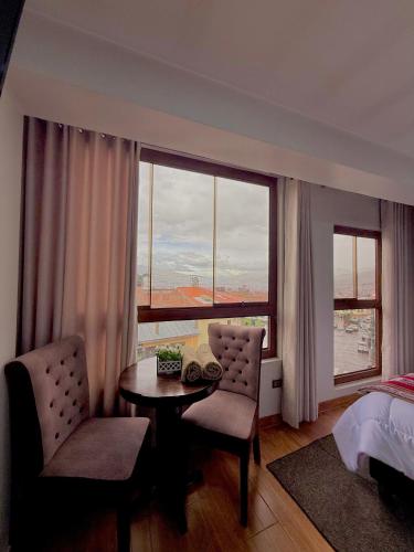 a bedroom with a table and chairs and a large window at Hospedaje chakana inn in Cusco