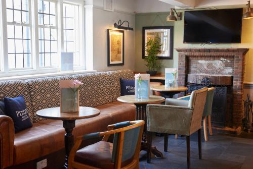 a restaurant with tables and a couch and a fireplace at St Leonards Hotel by Greene King Inns in Saint Leonards