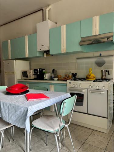 a kitchen with a table with chairs and a stove at L’Albero Colorato in Candelo