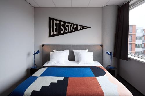 a bedroom with a bed with a sign that says lets stay in at The Social Hub Amsterdam West 4 star in Amsterdam