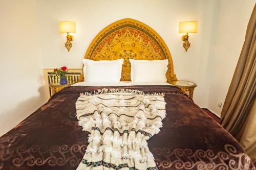 a bedroom with a large bed with a gold headboard at Villa Pomme d'Or in Midelt