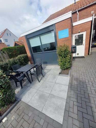 a patio with a table and benches in front of a building at 't Vakansie'uus in Serooskerke