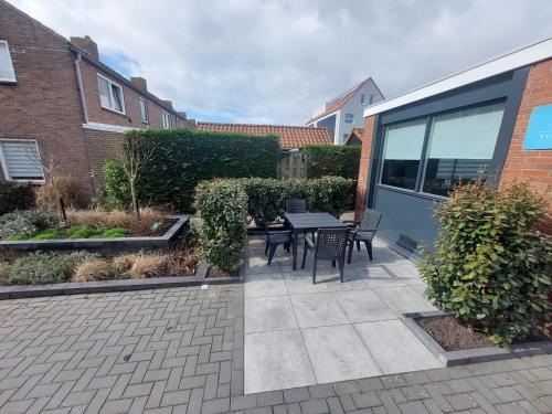 a patio with a table and chairs next to a building at 't Vakansie'uus in Serooskerke