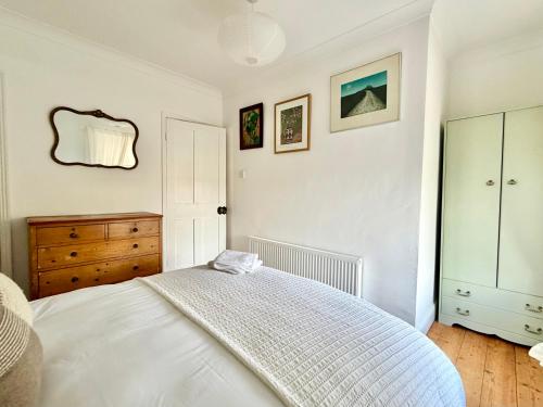 a white bedroom with a bed and a dresser at Carrstone Cottage, Snettisham in Snettisham