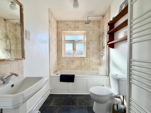 a bathroom with a tub and a toilet and a sink at Carrstone Cottage, Snettisham in Snettisham